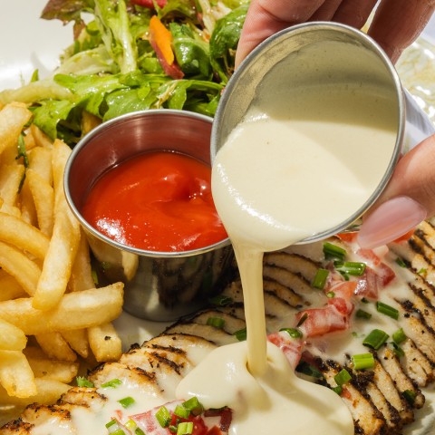 a person pouring sauce over a plate of food