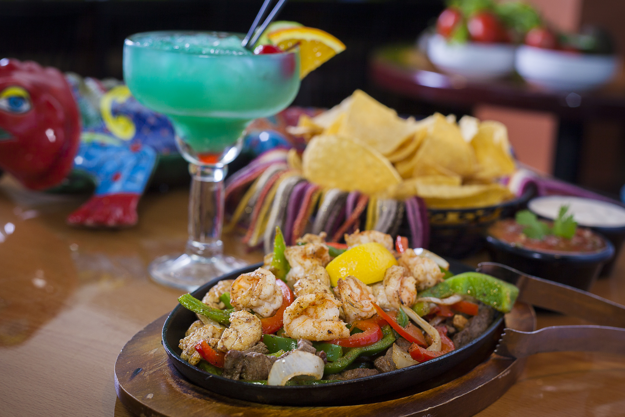 a plate of shrimp and vegetables on a table with a drink