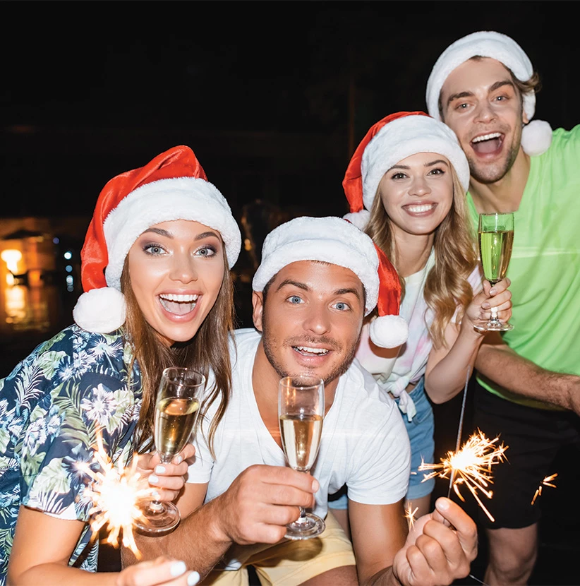 a group of people wearing santa hats holding champagne glasses
