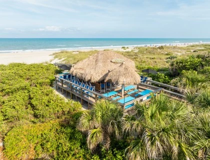 a hut with chairs and a thatched roof on a beach