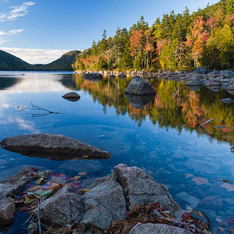 a lake with rocks and trees in the background