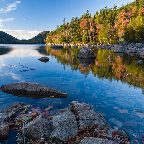 a lake with rocks and trees in the background