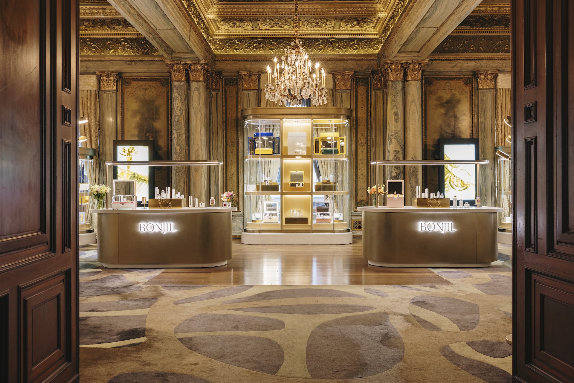 a room with a chandelier and shelves with perfumes