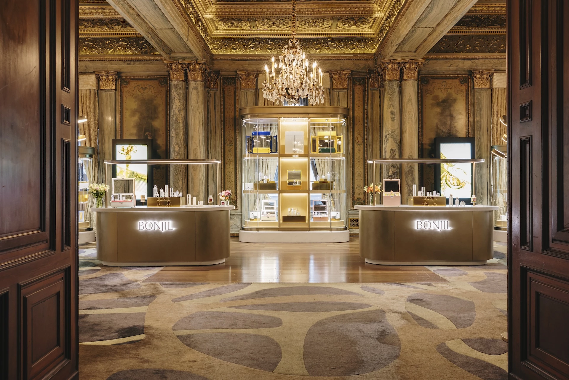 a room with a chandelier and shelves with perfumes