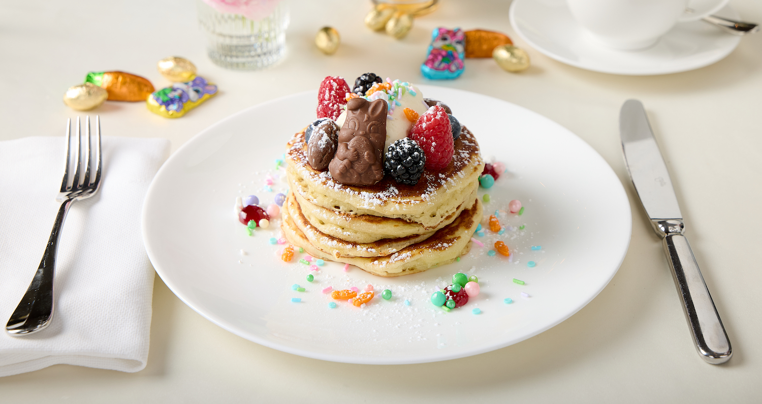 a stack of pancakes with berries and candy on top