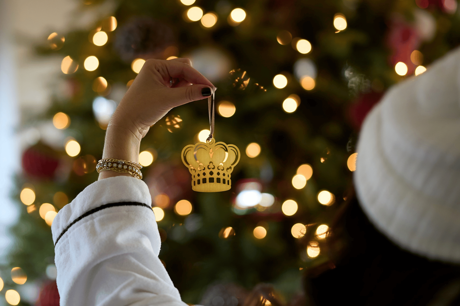 a hand holding a gold crown ornament