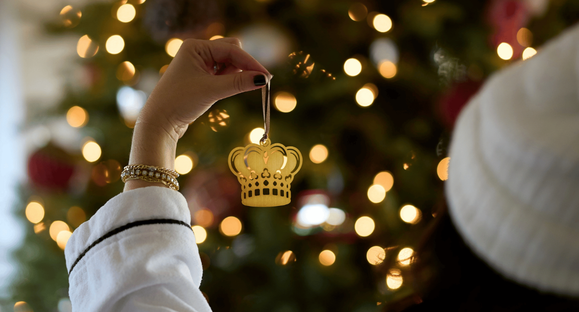 a hand holding a gold crown ornament