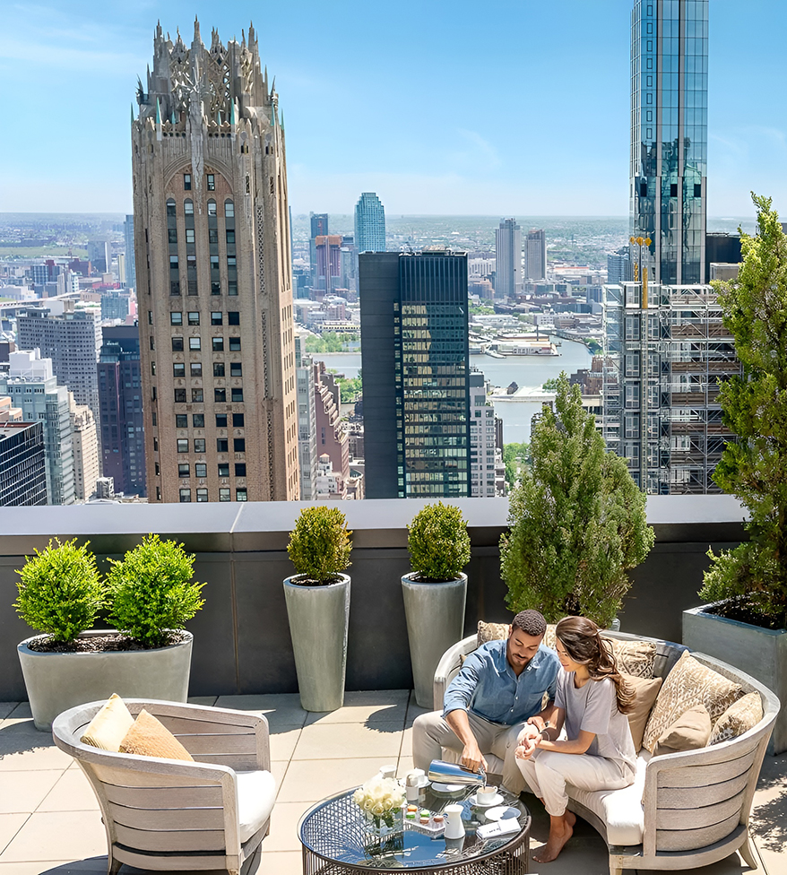 a man and woman sitting on a rooftop overlooking a city