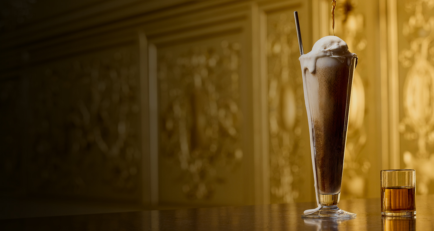 a glass of brown liquid with a straw