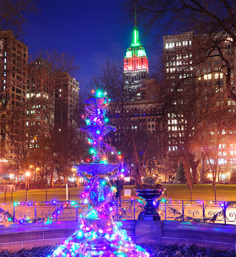 a fountain with lights in front of a city