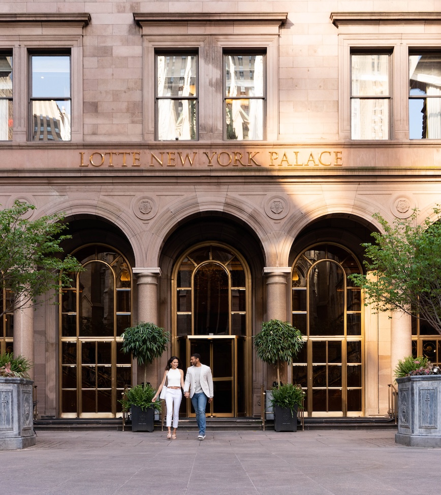 a man and woman walking out of the courtyard entrance of the hotel 