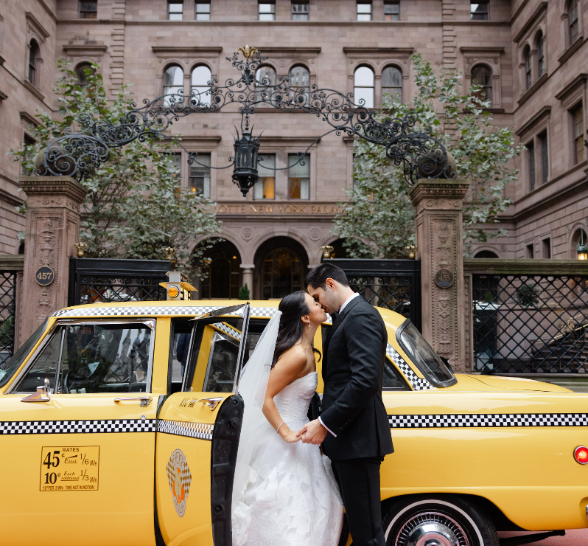 a man and woman kissing in front of a yellow taxi