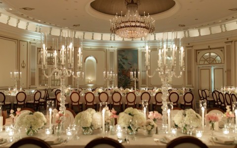 a room with a chandelier and tables with flowers and candles