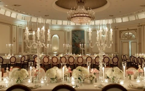 a room with a chandelier and tables with flowers and candles