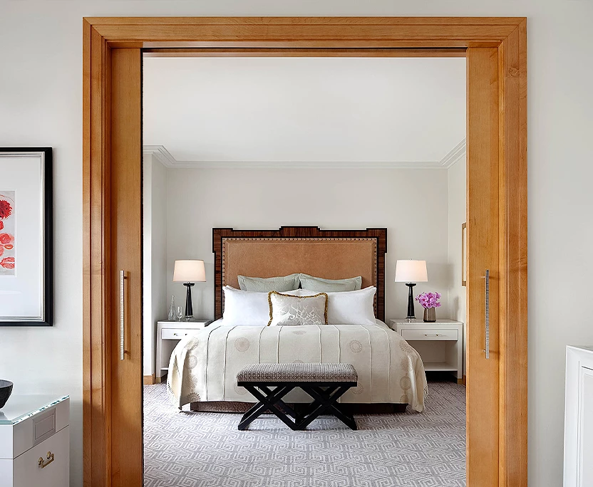 sliding wood doors framing a bedroom with white night stands and a brown headboard