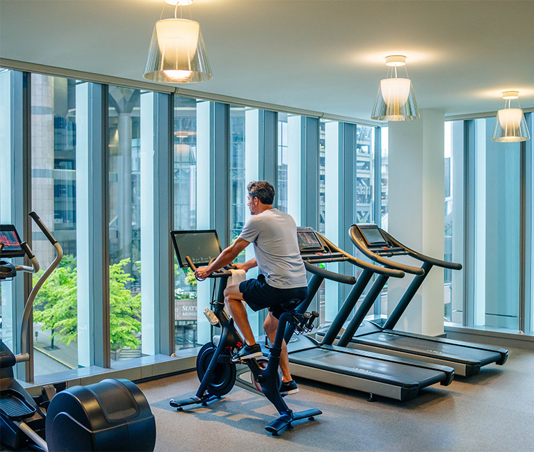 Man working out on a peloton in the fitness room overlooking the city