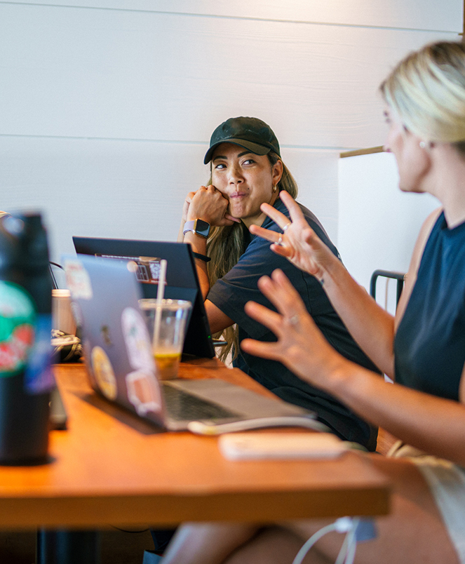 a group of women sitting at a table with laptops