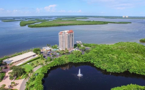 Aerial shot of hotel surrounded by greenery and body of water