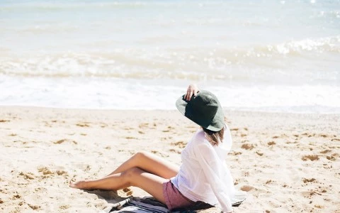 Woman sitting on sand by the water