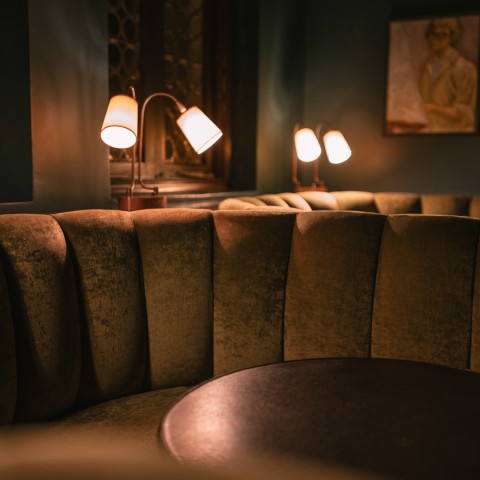a round brown couch with a round table and two lamps
