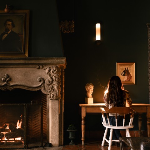 a woman sitting at a table by a fireplace