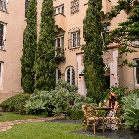 a woman sitting at a table outside of a building