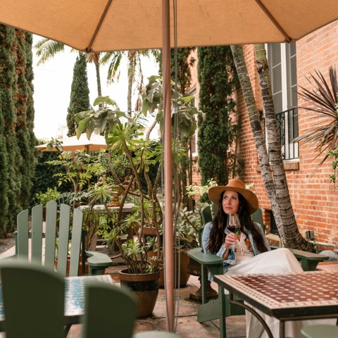 a woman sitting at a table under an umbrella