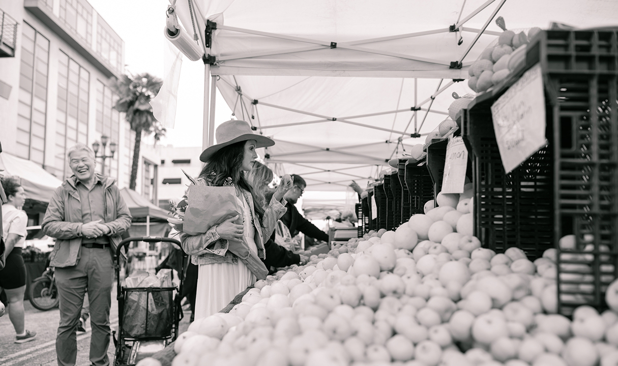 a woman standing in front of a fruit stand