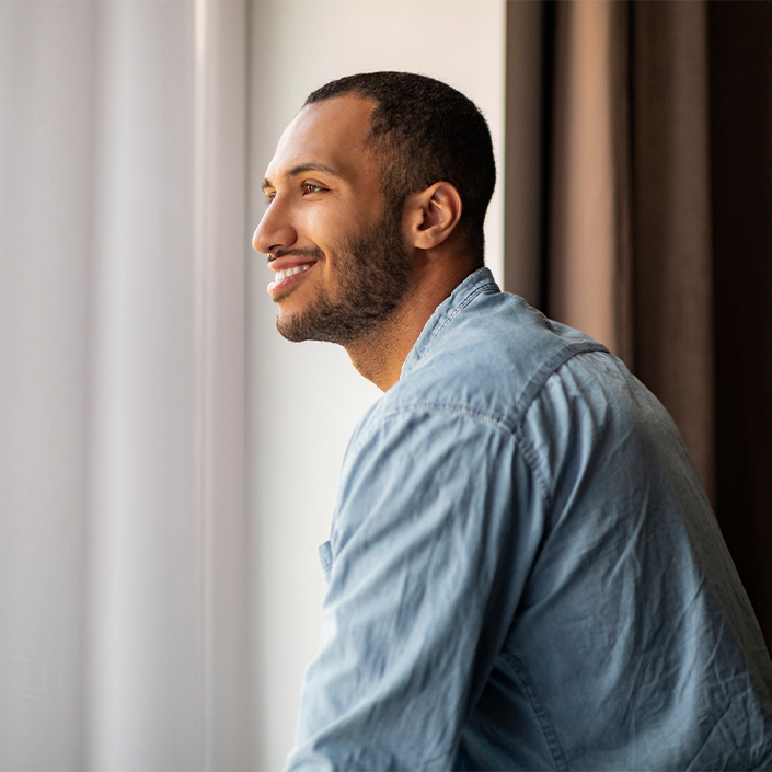 a man smiling and looking out a window