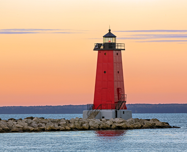 a red lighthouse on a rocky island
