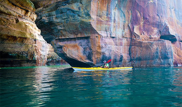 a person in a kayak under a rock