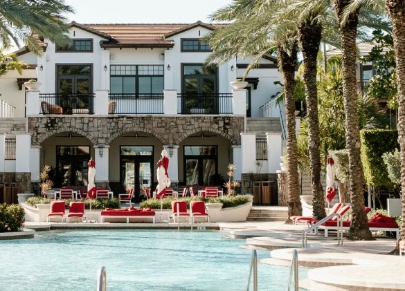 a pool with chairs and umbrellas in front of a building