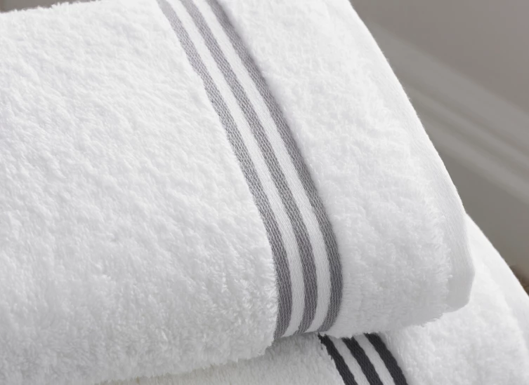 a stack of white towels with grey stripes