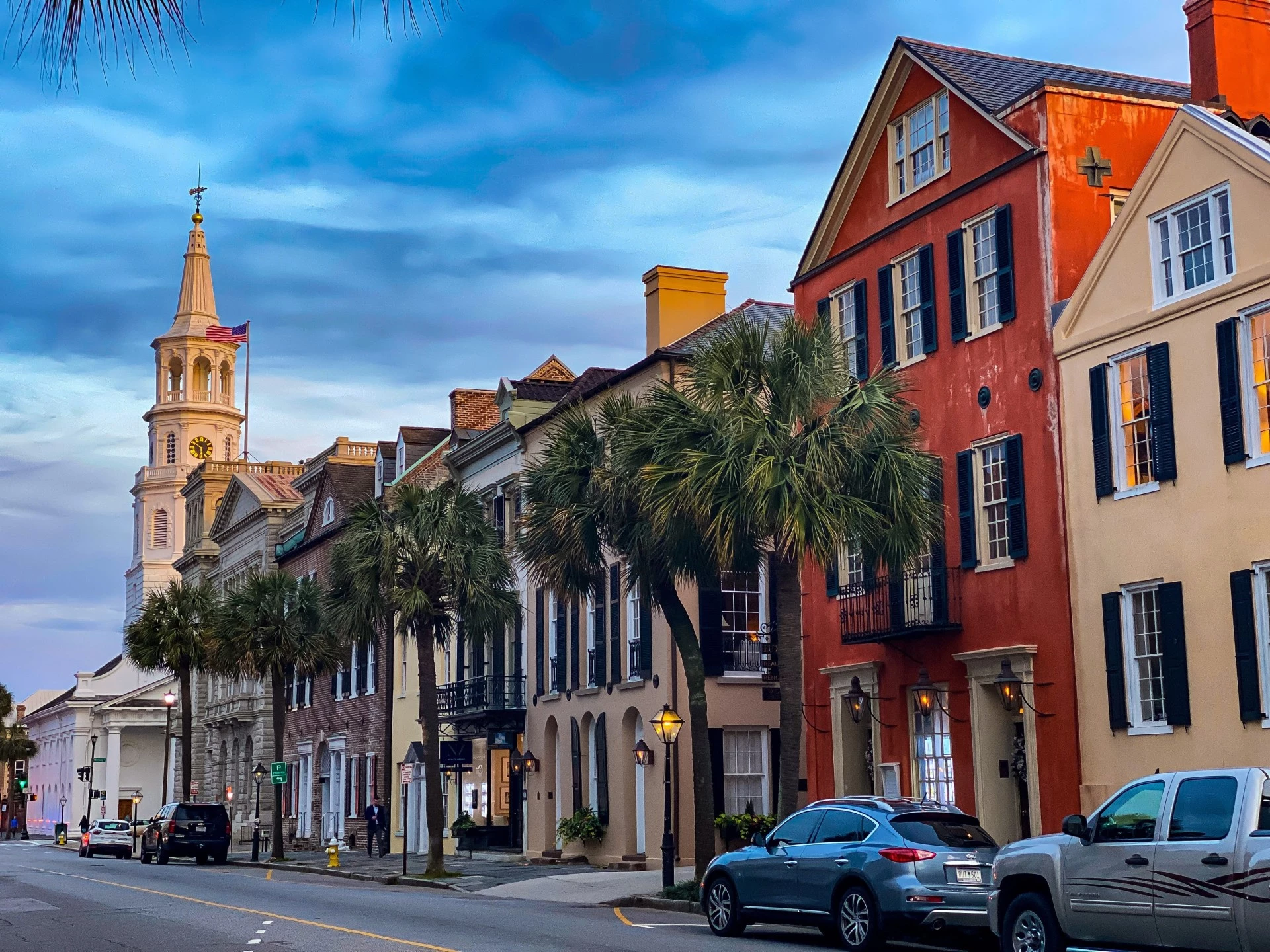 a row of colorful buildings with palm trees and a tower