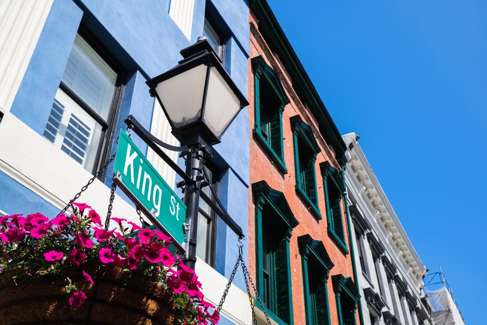 a street sign and a lamp post with flowers in front of a building