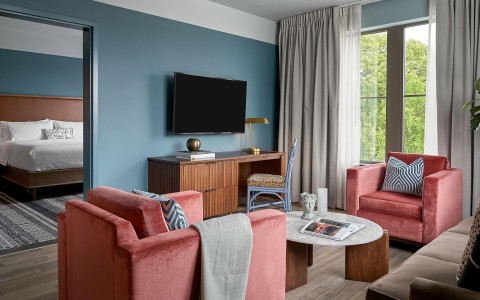 A room with two large pink chairs and a tv