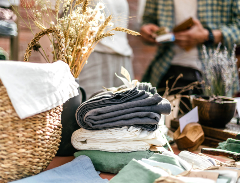 a stack of folded clothes and a basket of flowers