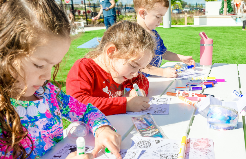 a group of children coloring on paper at a table
