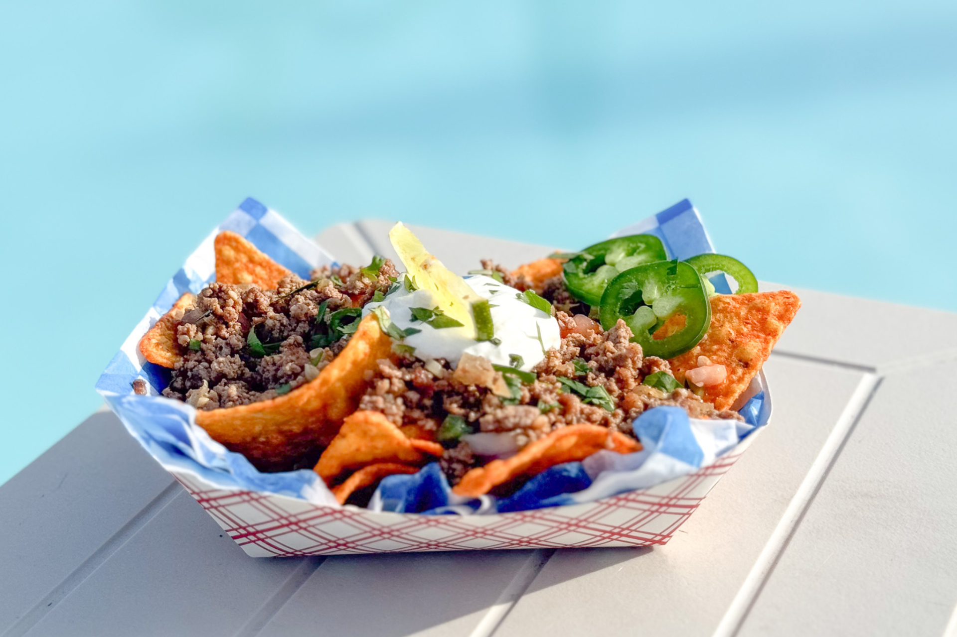 a bowl of nachos with meat and jalapenos