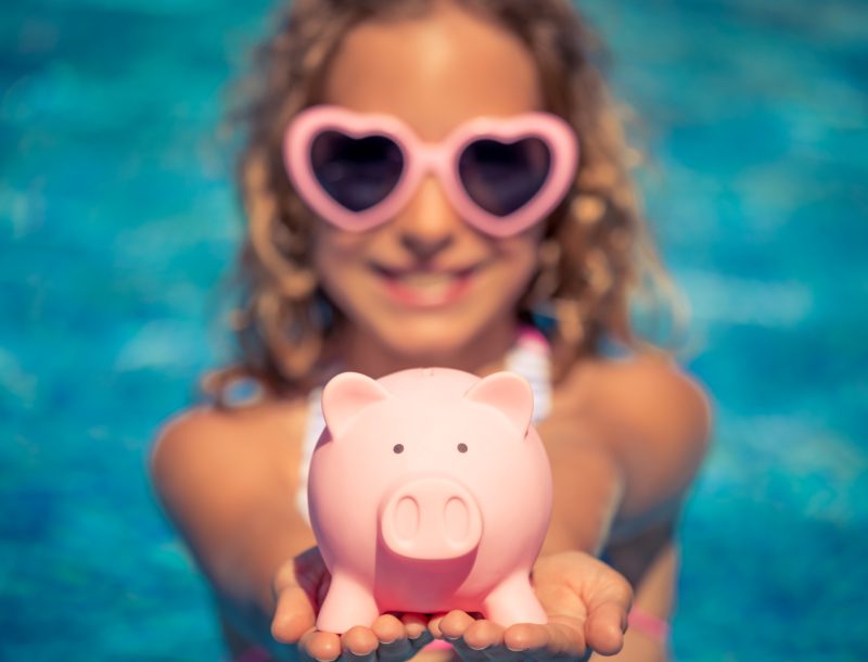 a girl holding a piggy bank in a pool
