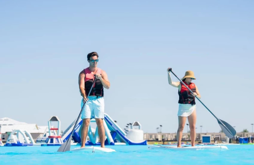 a man and woman on paddle boards in a pool