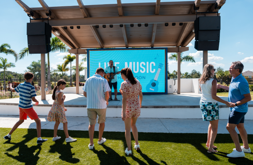 a group of people standing on grass under a screen