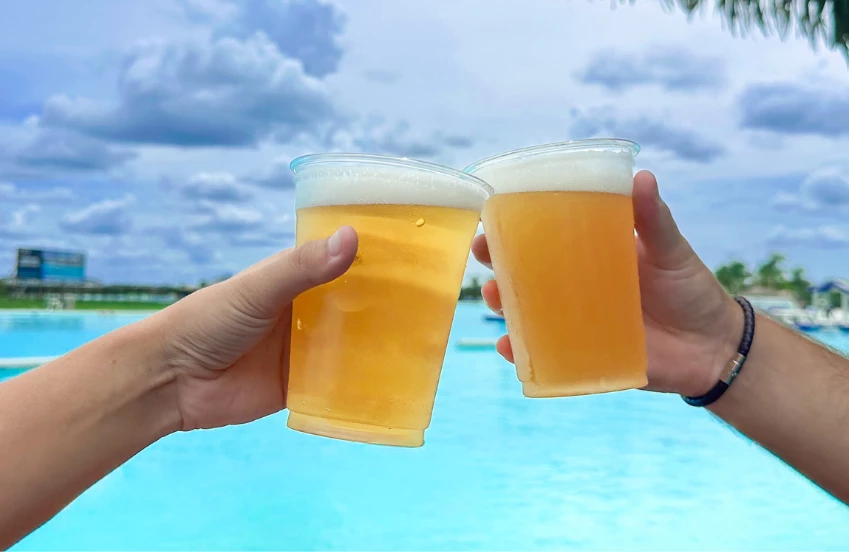 two hands holding cups of beer