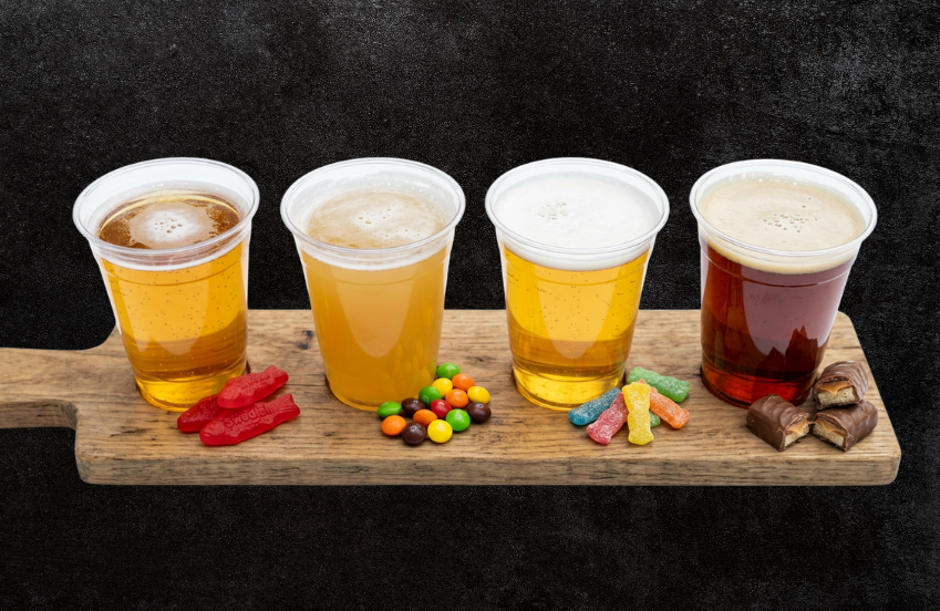 a row of plastic cups with liquid and candy on a wooden surface