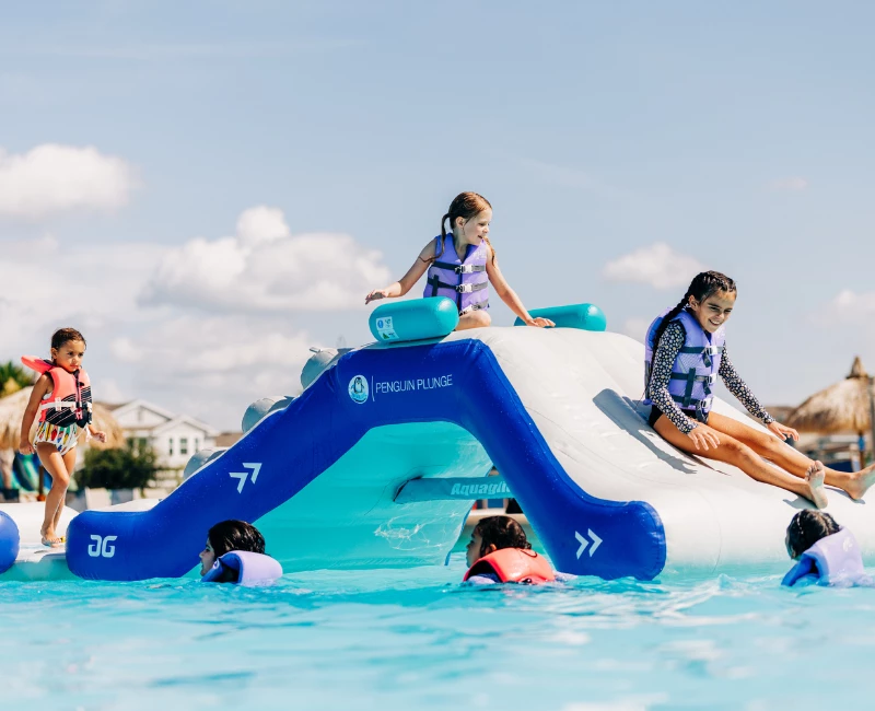 a group of kids on a water slide in a pool
