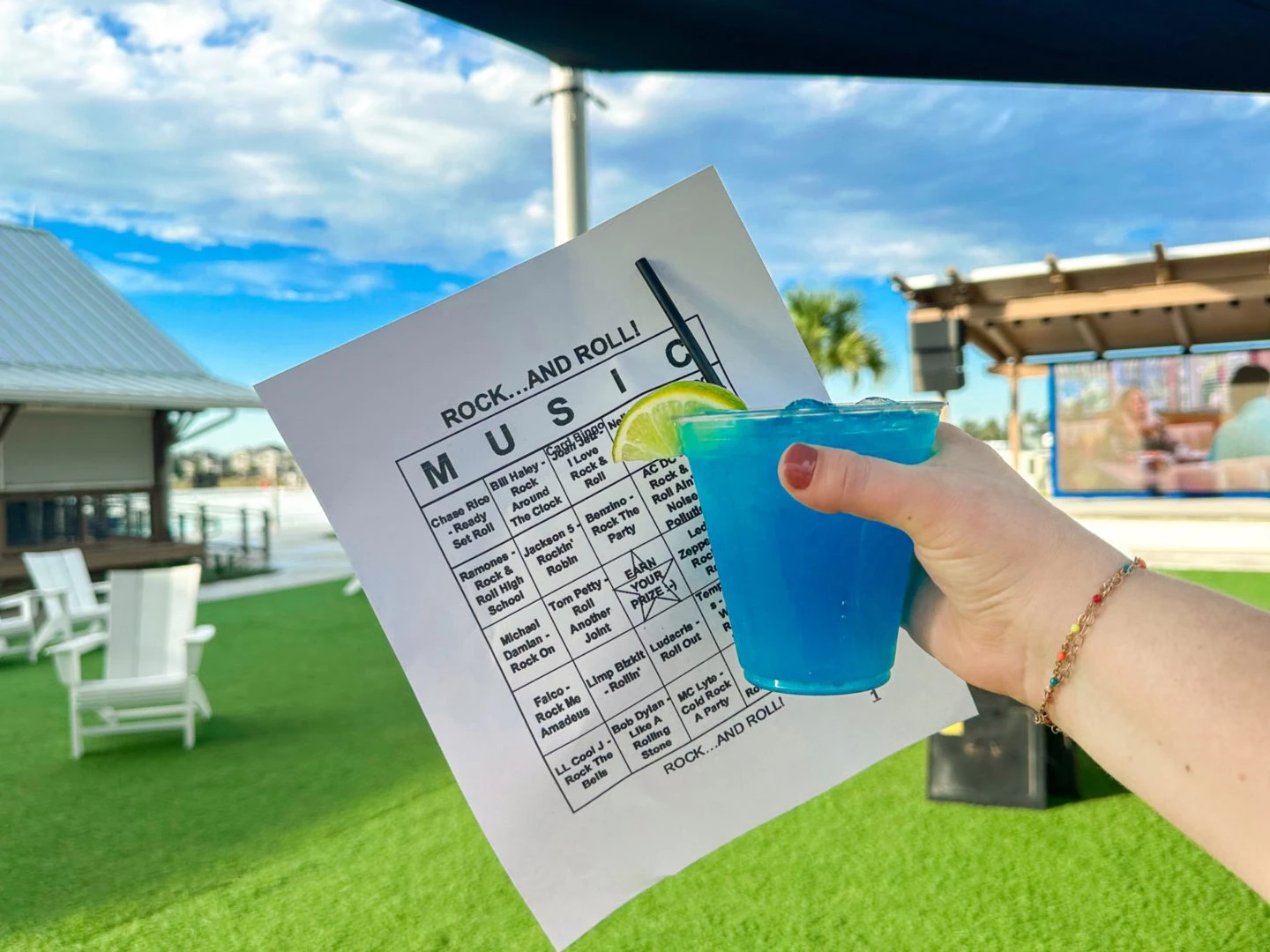 a hand holding a blue drink with a piece of paper and a straw