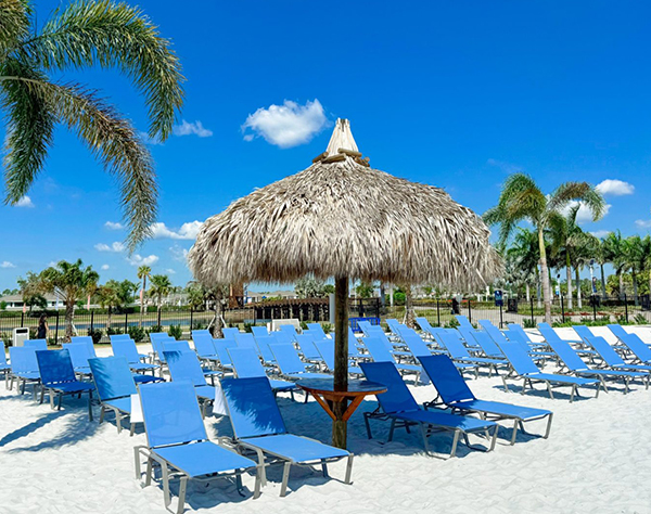 a group of blue chairs and a straw umbrella on a beach