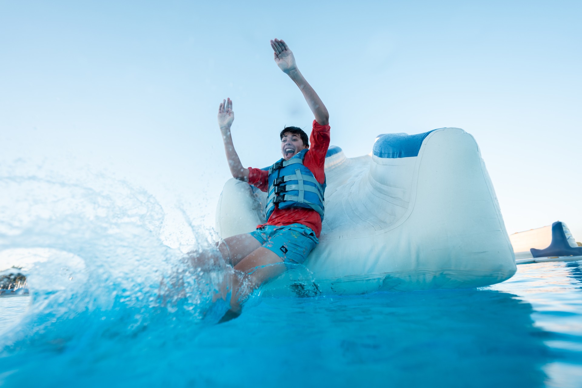 a boy in a life jacket on a floating object in water