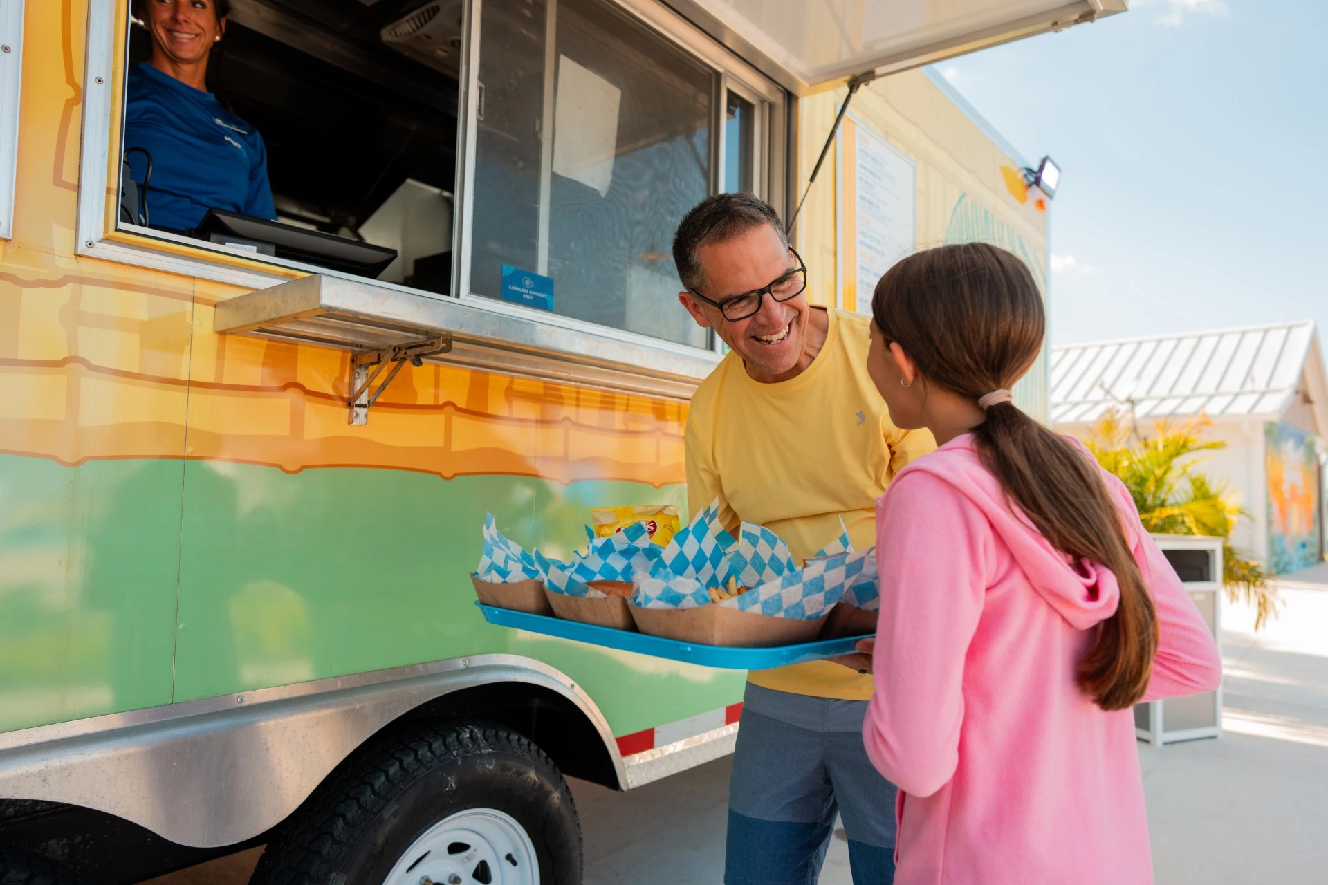 a man and girl standing next to a food truck
