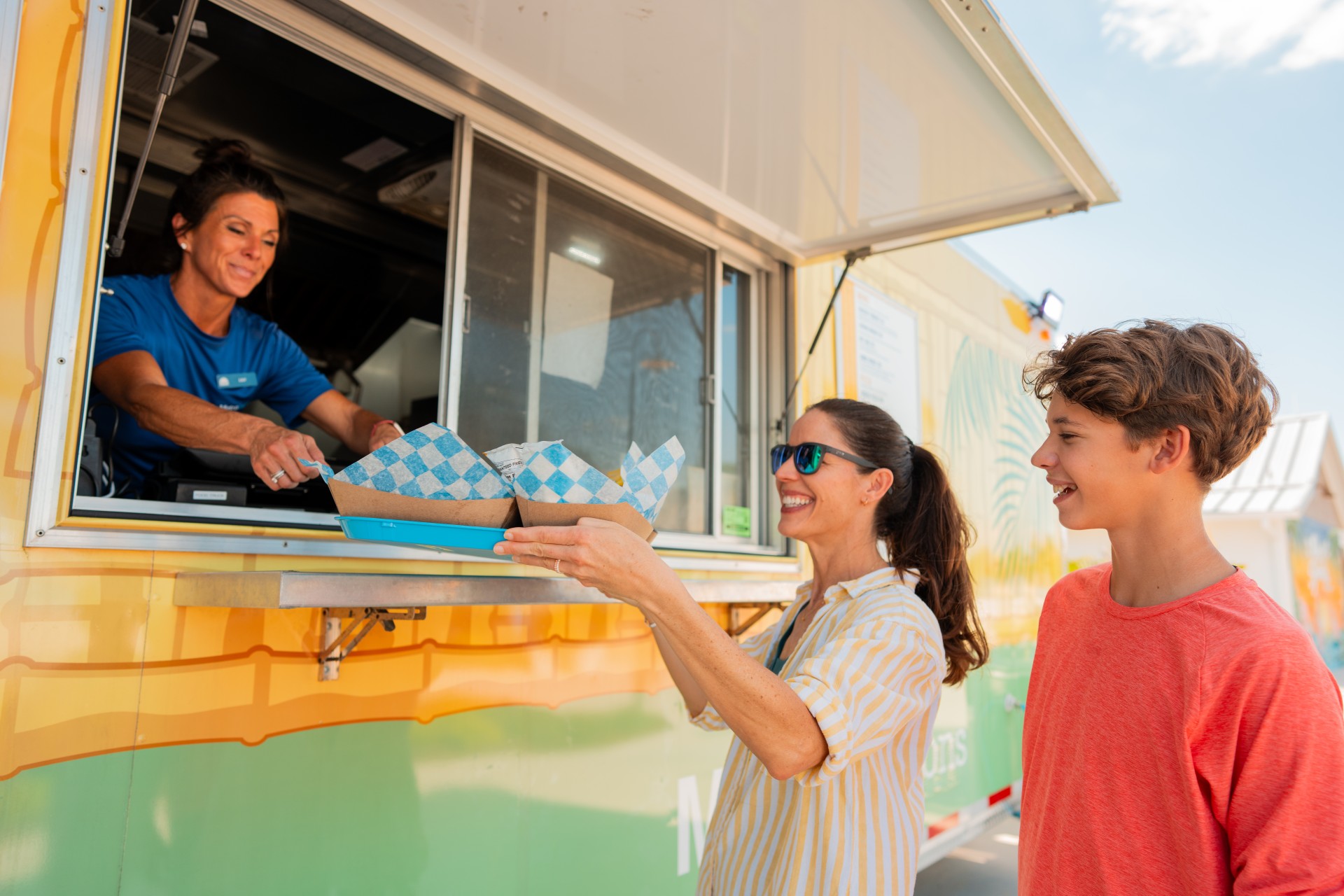 a woman handing food to a boy